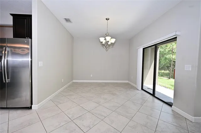 a view of an empty room with window and chandelier fan