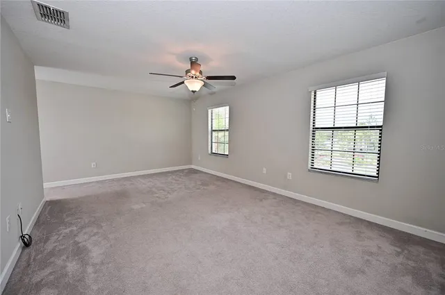 an empty room with windows and ceiling fan