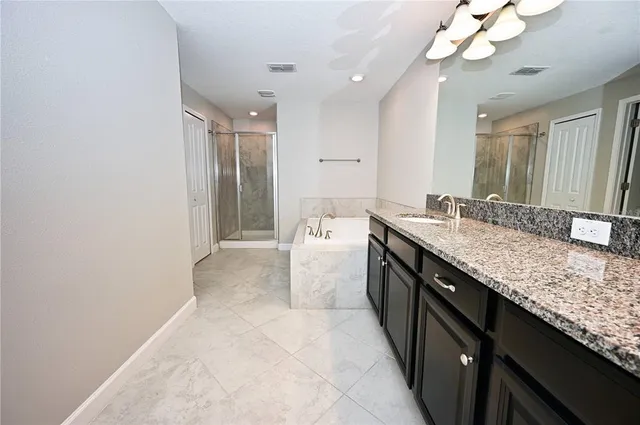 a spacious bathroom with a granite countertop double vanity and a mirror