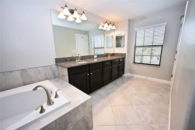 a spacious bathroom with a granite countertop bathtub a sink and a mirror