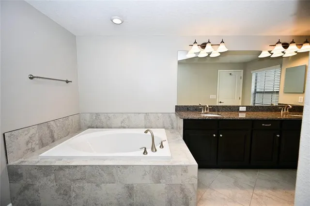 a bathroom with a tub sink and mirror