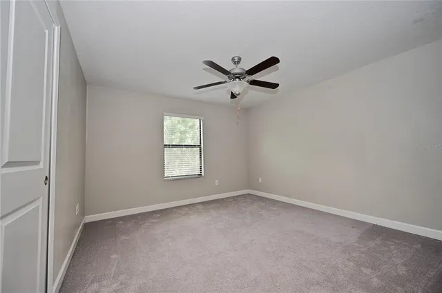 an empty room with a window and a fan