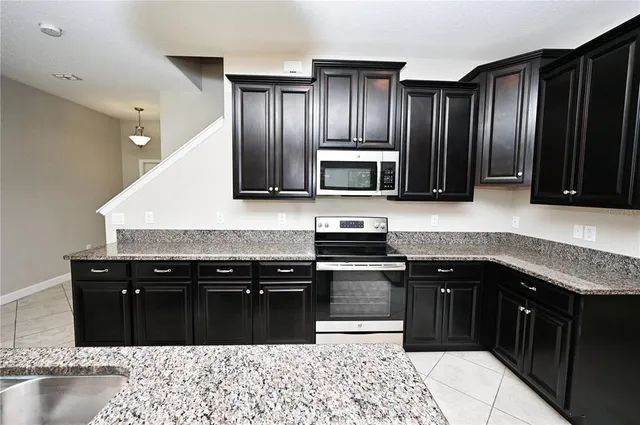 a kitchen with stainless steel appliances granite countertop wooden cabinets a stove top oven and granite counter tops
