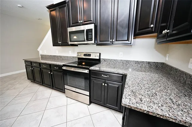 a kitchen with granite countertop a sink stove and microwave