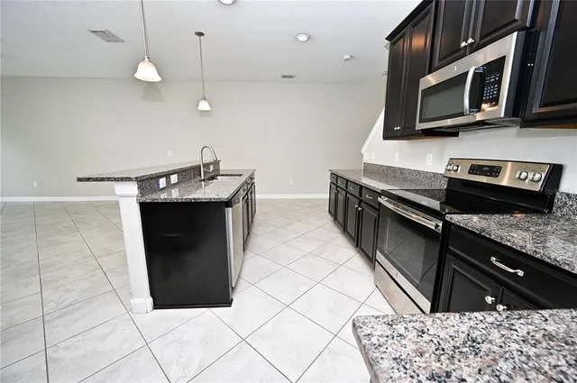 a kitchen with stainless steel appliances granite countertop a stove a microwave and a sink