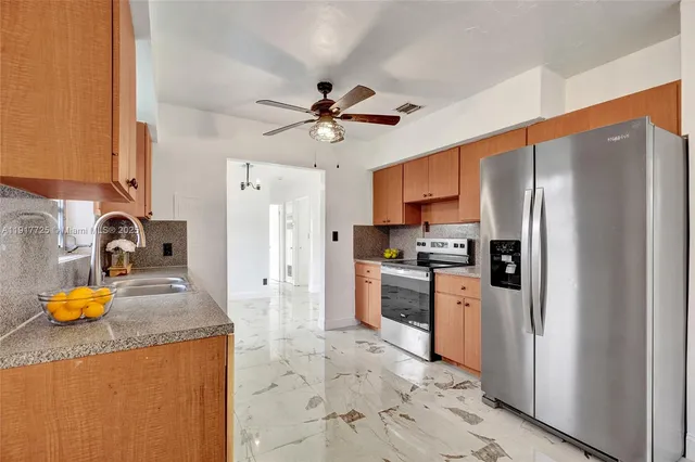 a kitchen with stainless steel appliances granite countertop a refrigerator a stove and a sink