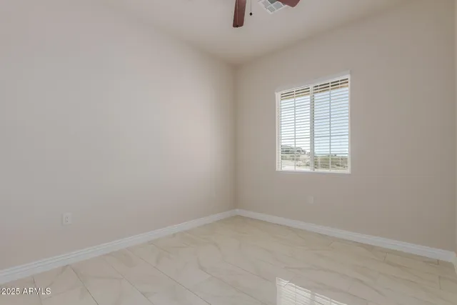 an empty room with a window and a fan