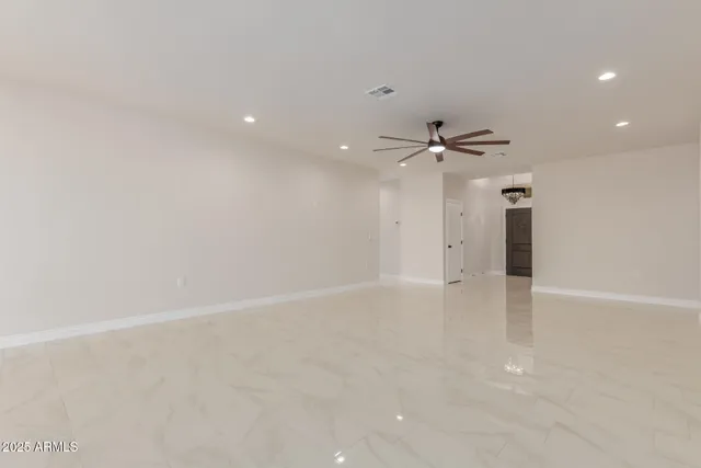 a view of an empty room with window and kitchen view
