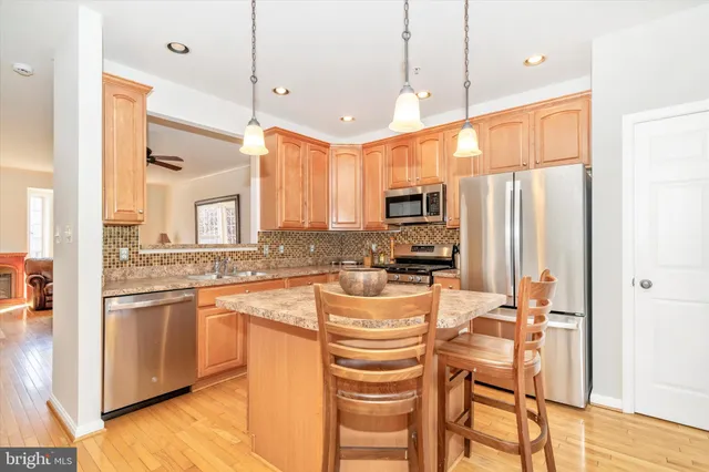 a kitchen with stainless steel appliances kitchen island granite countertop a stove a sink and a refrigerator