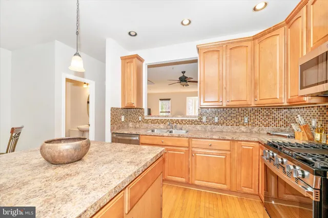 a kitchen with stainless steel appliances granite countertop a sink a stove and a wooden floors