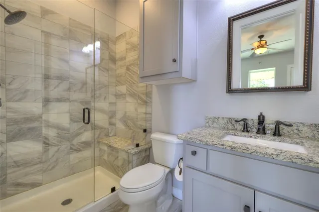 a bathroom with a granite countertop sink toilet and shower
