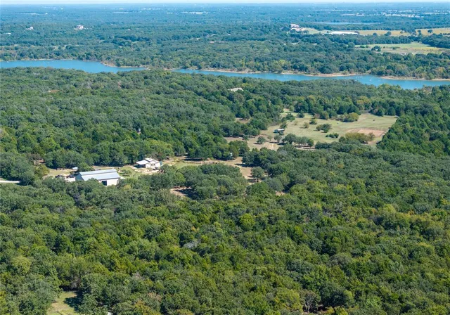 an aerial view of residential house with outdoor space and trees all around