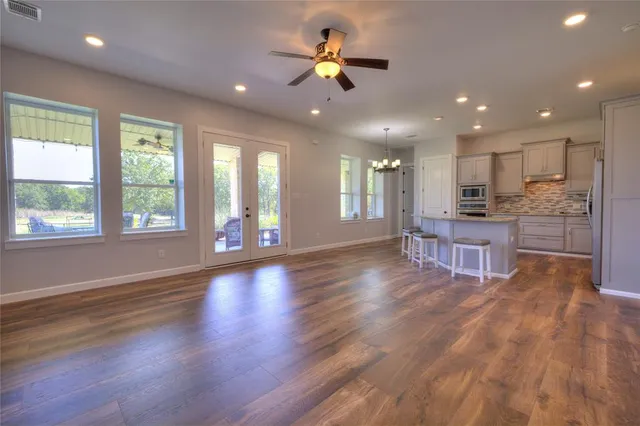 a view of an empty room with kitchen and window