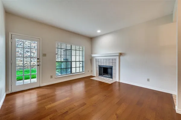 a view of empty room with wooden floor and fireplace