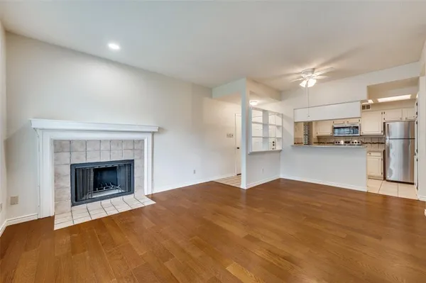 a view of empty room with kitchen and fireplace