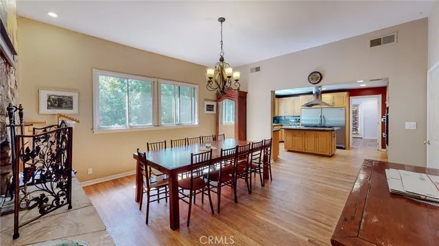 a kitchen with stainless steel appliances granite countertop a stove top oven a sink with wooden cabinets and dining table