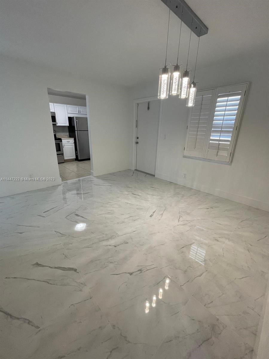 5790 Stirling Road, Unit 205 Hollywood, FL 33021 - Photo 9 of 28 a view of an empty room with chandelier fan and kitchen view