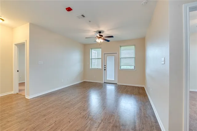 a view of an empty room with a window and wooden floor