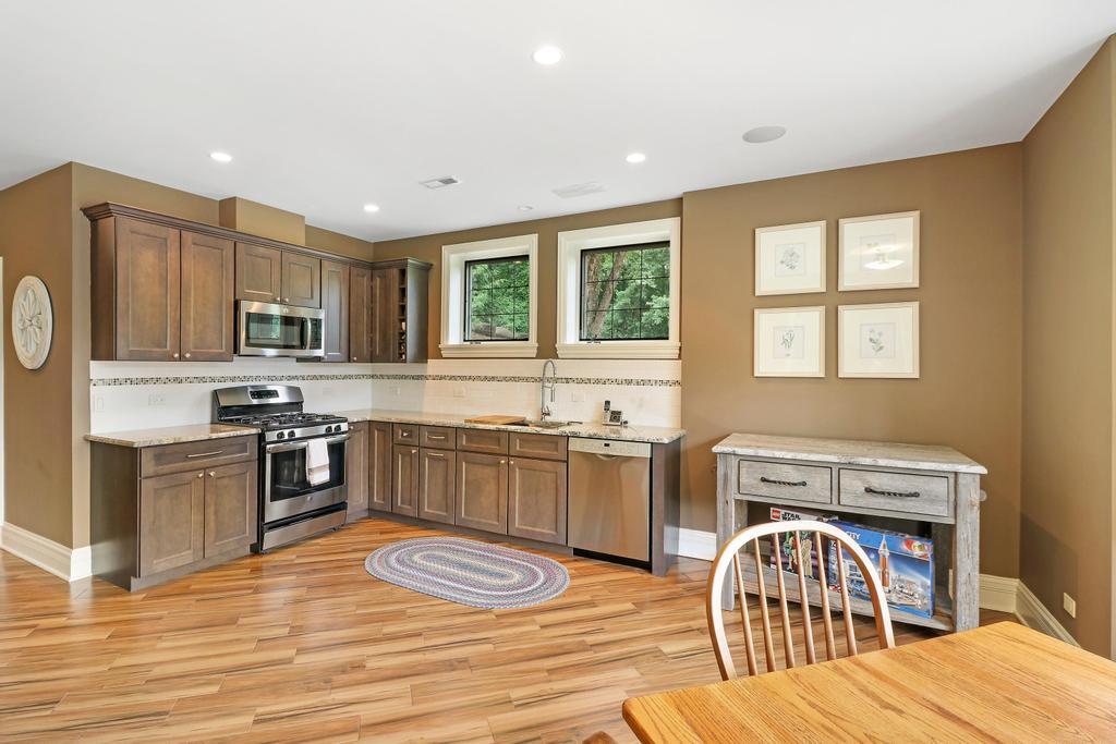 385 Spring Creek Road Barrington Hills, IL 60010 - Photo 39 of 53 a kitchen with stainless steel appliances granite countertop a stove top oven a sink dishwasher a dining table and chairs with wooden floor