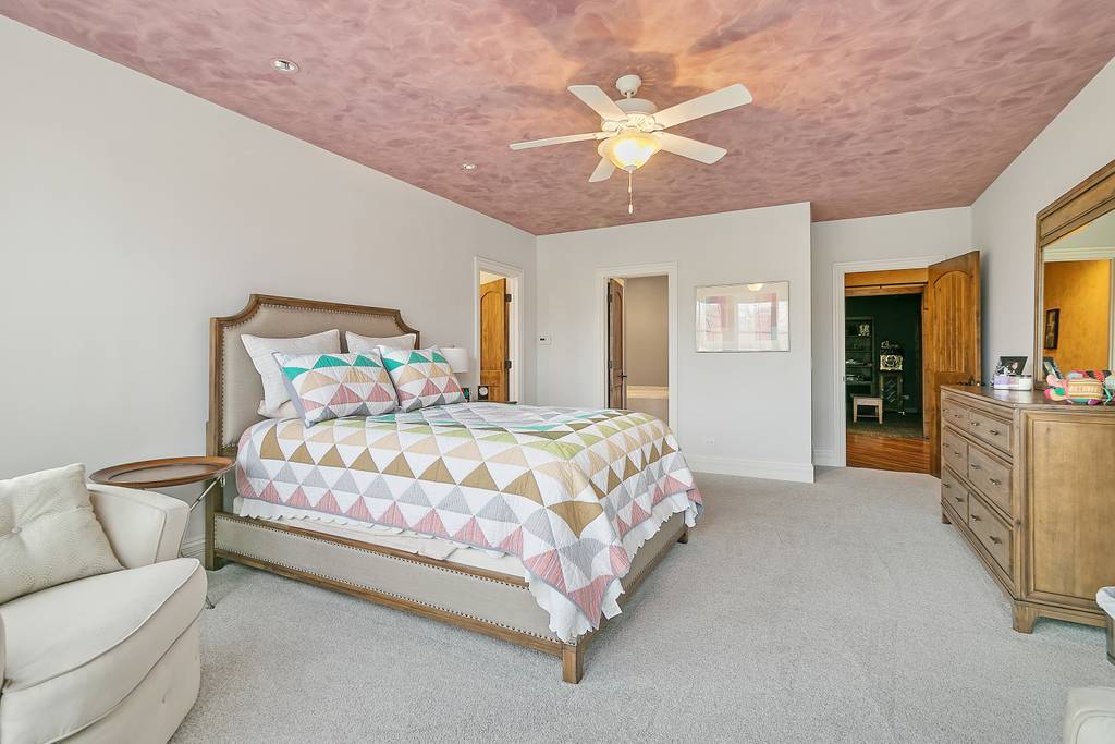 385 Spring Creek Road Barrington Hills, IL 60010 - Photo 41 of 53 a spacious bedroom with a bed and a chandelier