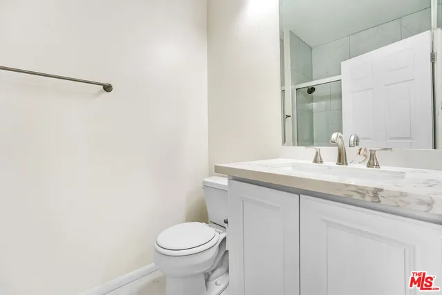 a bathroom with a granite countertop sink and a toilet
