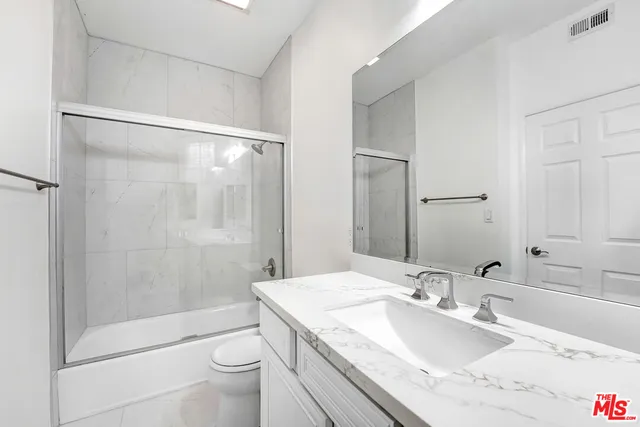 a bathroom with a granite countertop sink a toilet and shower