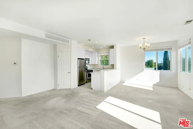 a large white kitchen with kitchen island a sink stainless steel appliances and cabinets
