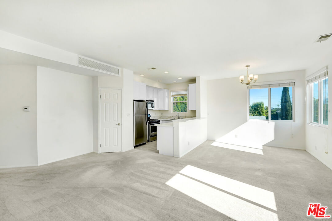 5430 Bellingham Avenue, Unit 306 Valley Village, CA 91607 - Photo 4 of 23 a large white kitchen with kitchen island a sink stainless steel appliances and cabinets