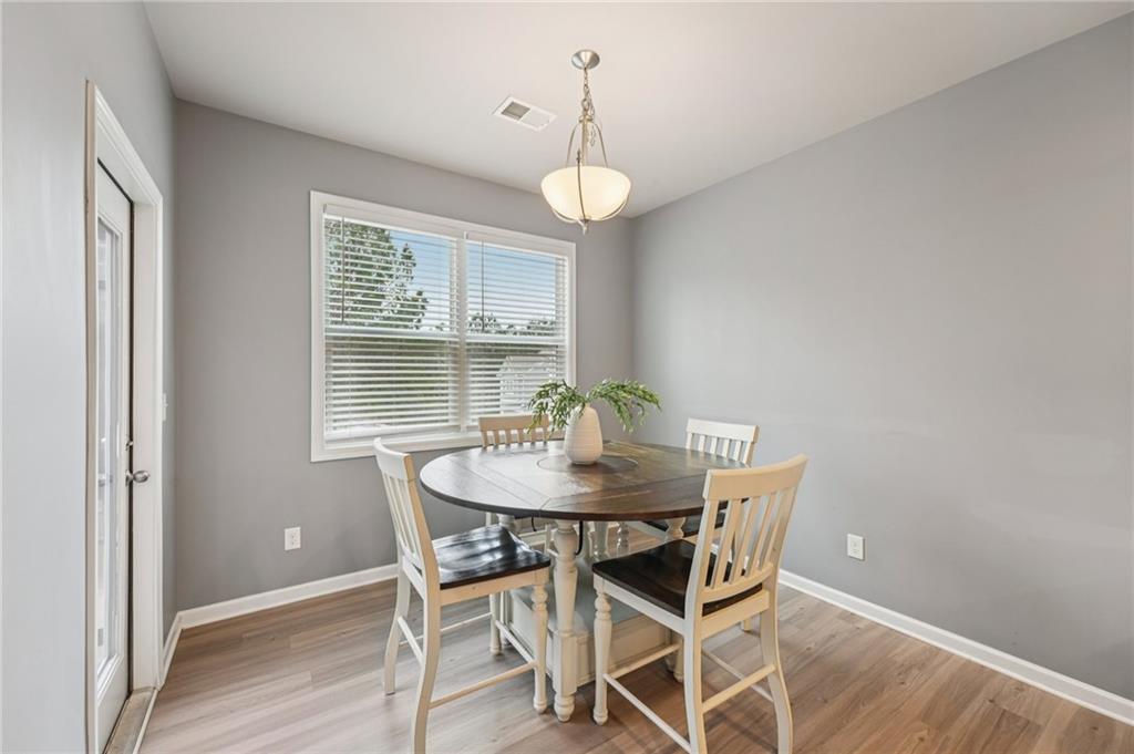 95 Denver Avenue Hiram, GA 30141 - Photo 14 of 62 a dining room with wooden floor a chandelier a wooden table and chairs