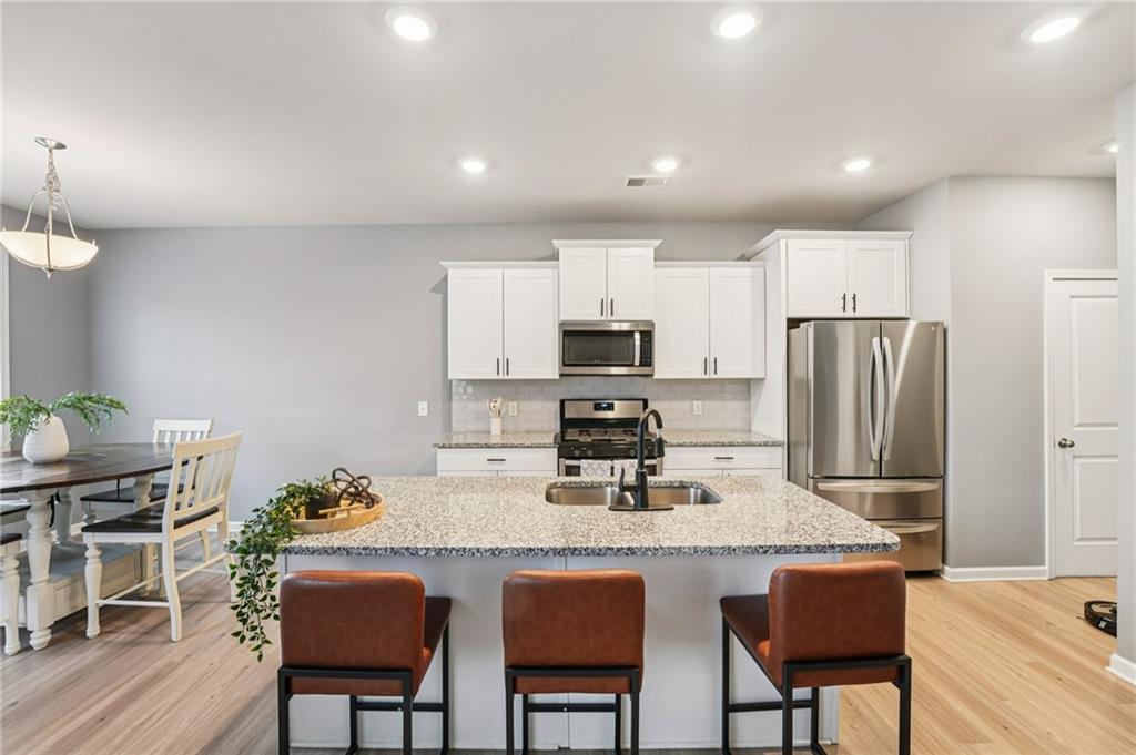 95 Denver Avenue Hiram, GA 30141 - Photo 20 of 62 a kitchen with granite countertop a dining table chairs refrigerator and cabinets