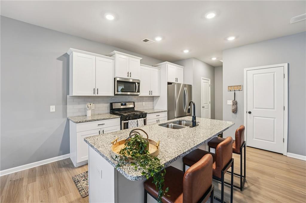 95 Denver Avenue Hiram, GA 30141 - Photo 21 of 62 a kitchen with stainless steel appliances granite countertop a stove top oven a refrigerator a sink and a dining table with wooden floor