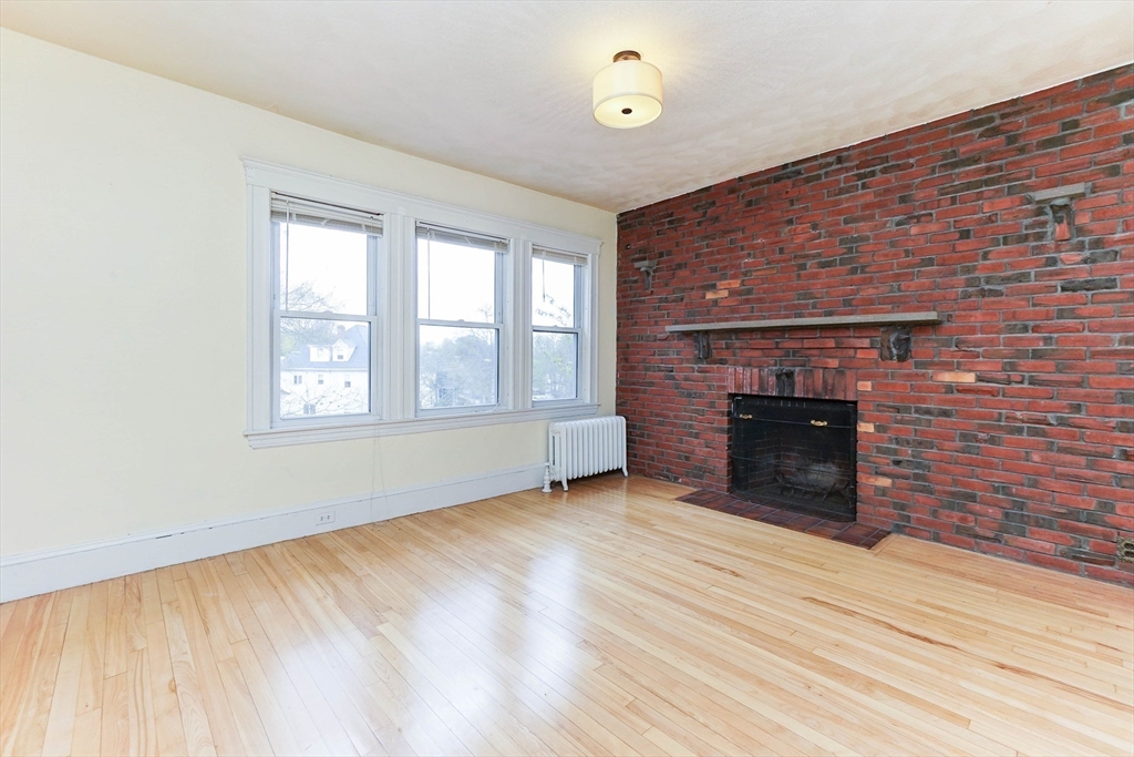 51 Wallingford Road Boston, MA 02135 - Photo 12 of 42 a view of empty room with wooden floor and fireplace