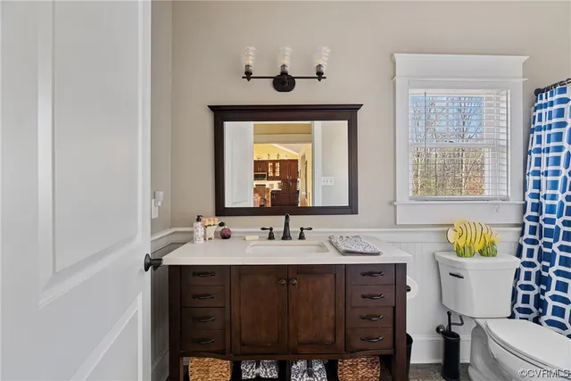 a bathroom with a granite countertop sink a toilet and a mirror