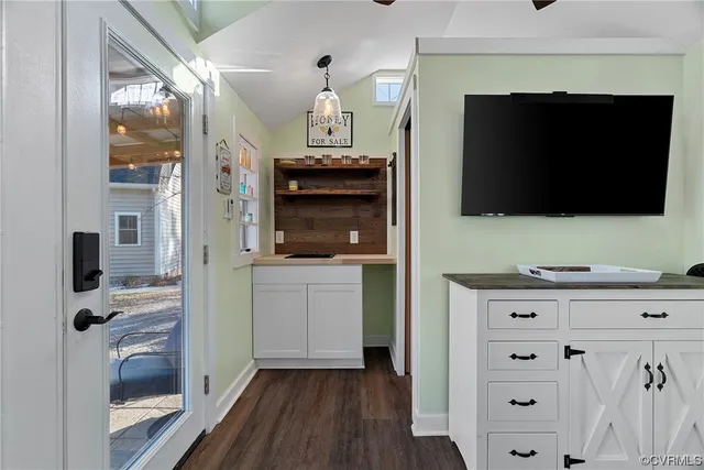a living room with stainless steel appliances wooden floor a fireplace and a television