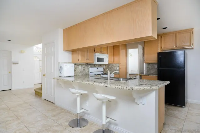 a kitchen with stainless steel appliances granite countertop a sink refrigerator and cabinets