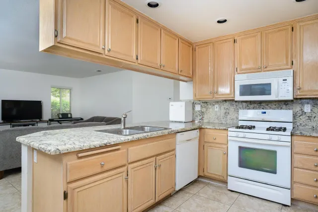 a kitchen with granite countertop white cabinets sink and stainless steel appliances