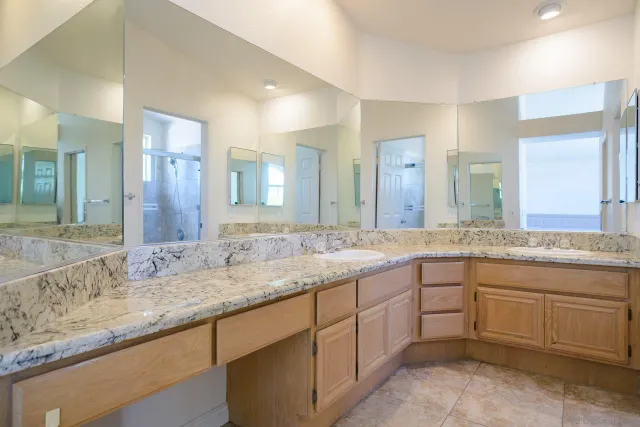 a bathroom with a granite countertop double sink and a large mirror