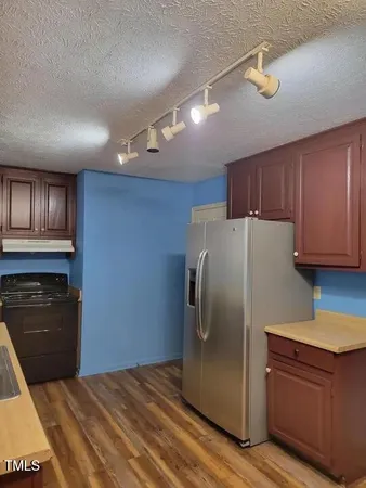 a kitchen with stainless steel appliances granite countertop a refrigerator a stove and a sink with wooden floor