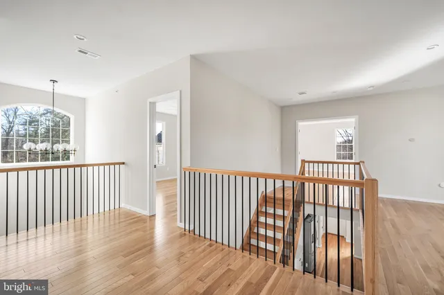 an empty room with wooden floor chandelier fan and windows