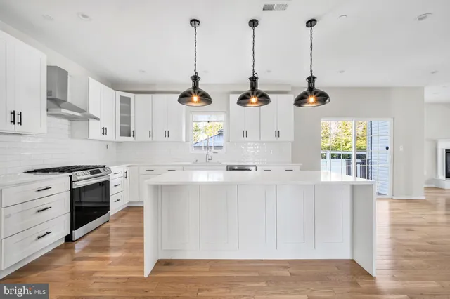 a open kitchen with white cabinets and wooden floor