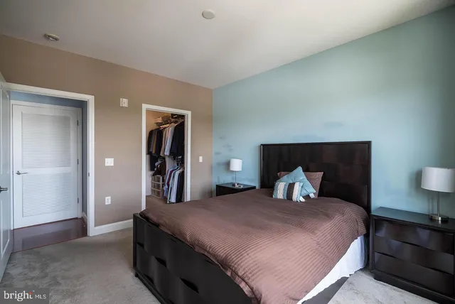 a bedroom with a large bed and a lamp on dresser