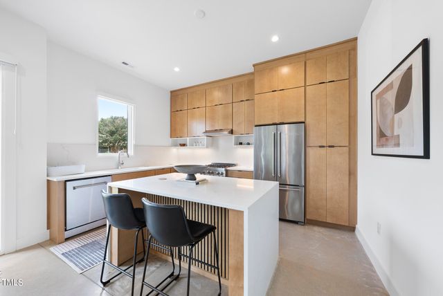 a kitchen with stainless steel appliances a table and chairs