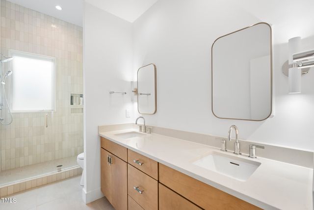 a bathroom with a double vanity sink mirror and shower
