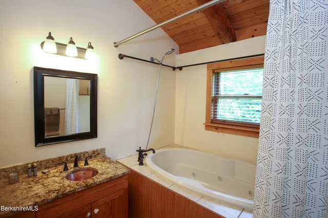 a bathroom with a granite countertop sink and a bathtub