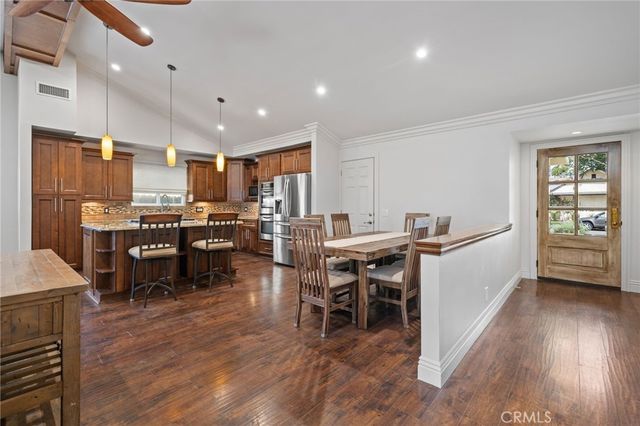 a kitchen with stainless steel appliances kitchen island granite countertop a refrigerator a stove a sink a dining table and chairs with wooden floor