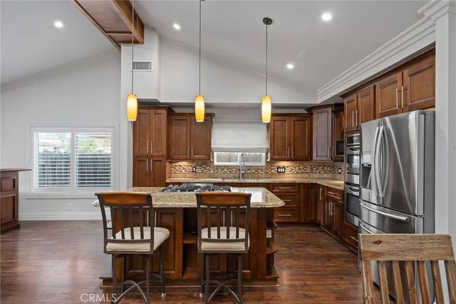 a kitchen with stainless steel appliances granite countertop a stove a refrigerator a kitchen island a table and chairs