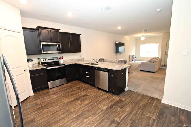 a kitchen with stainless steel appliances granite countertop wooden cabinets a sink dishwasher a stove and a refrigerator