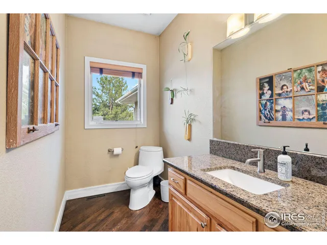 a bathroom with a granite countertop sink toilet and painting on the wall