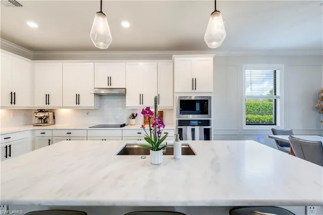 a kitchen with kitchen island granite countertop a sink a center island and stainless steel appliances