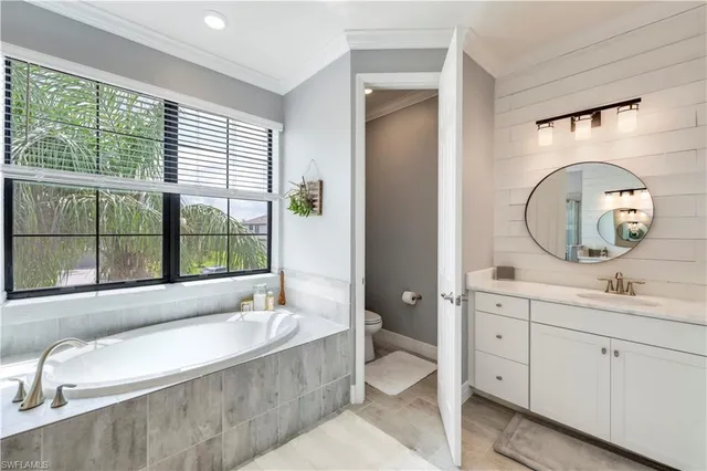a spacious bathroom with a tub mirror and window